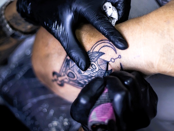 Een foto van een tatoeëerder bij het uitoefenen van zijn job